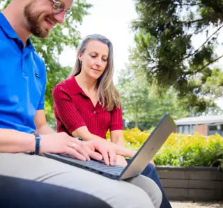Man laptop op schoot plus vrouw